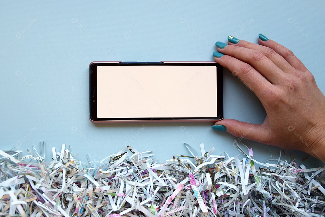 Textura de papéis cortados e mão segurando celular sobre fundo azul