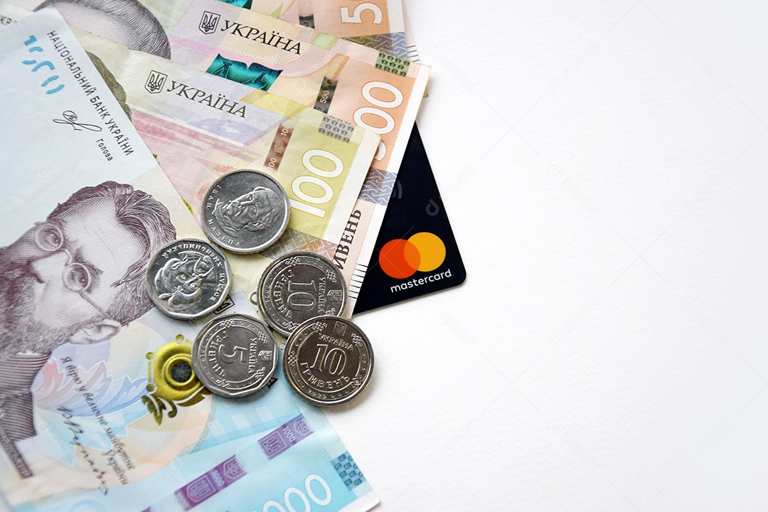 Moedas e dinheiro ucraniano e cartão de crédito sobre fundo branco
