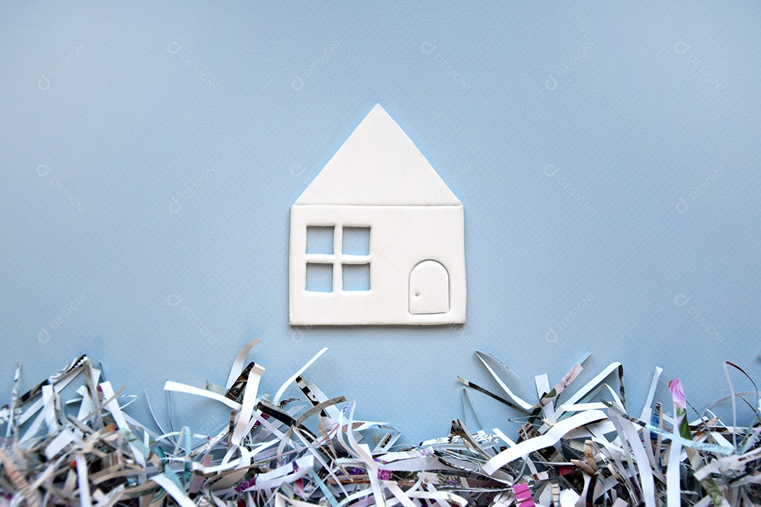 Mini casa de papel sobre fundo azul e papéis picados em baixo