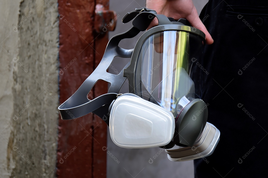 Mão de homem segurando mascara respiratória
