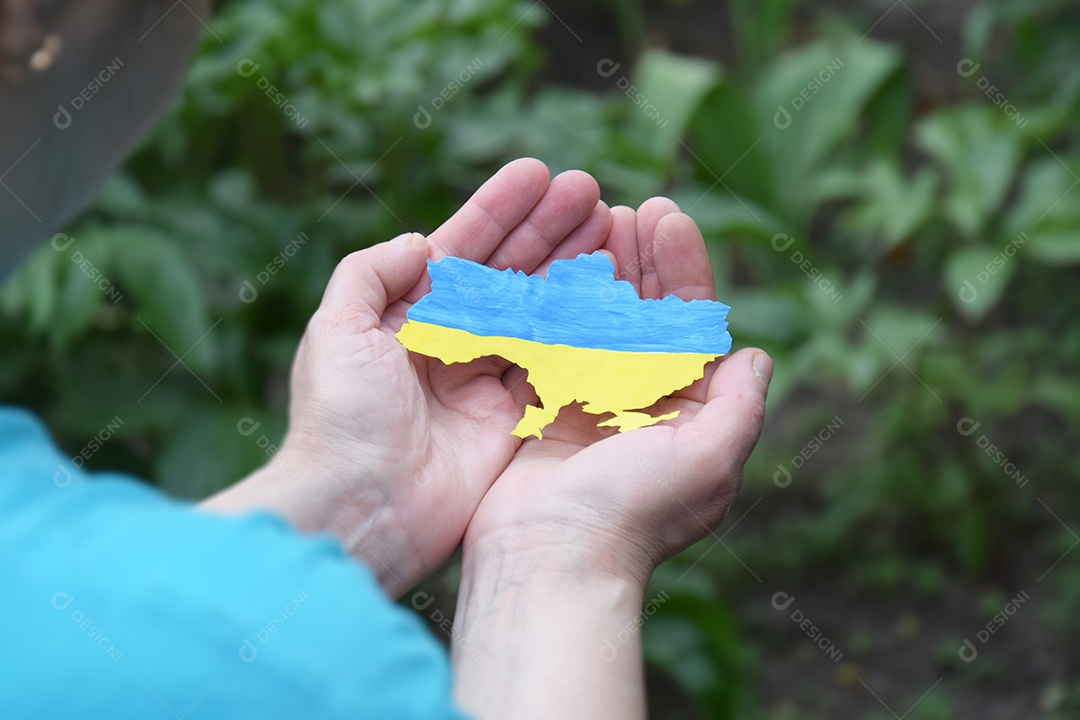 Mulher tem nas mãos o contorno do país Ucrânia decorado com cor da bandeira