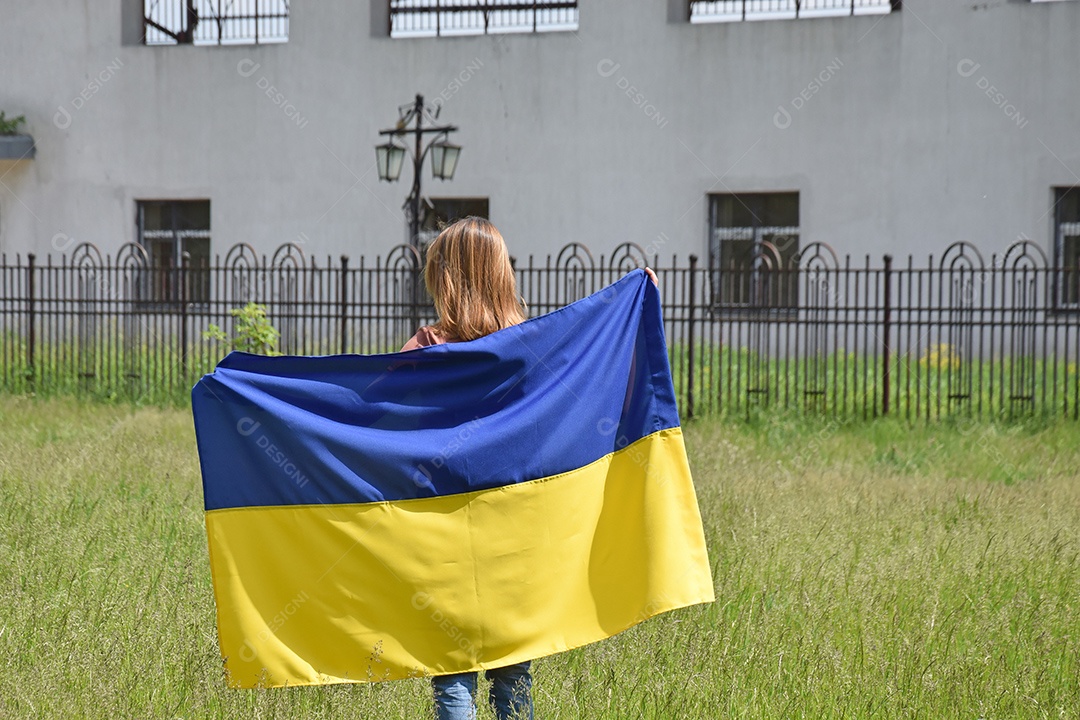 Mulher segurando bandeira em meio a destruição de guerra