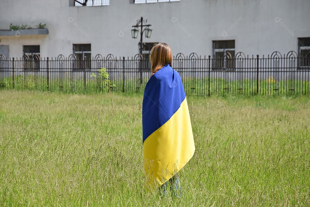 Mulher com bandeira nas costas vendo a destruição da guerra