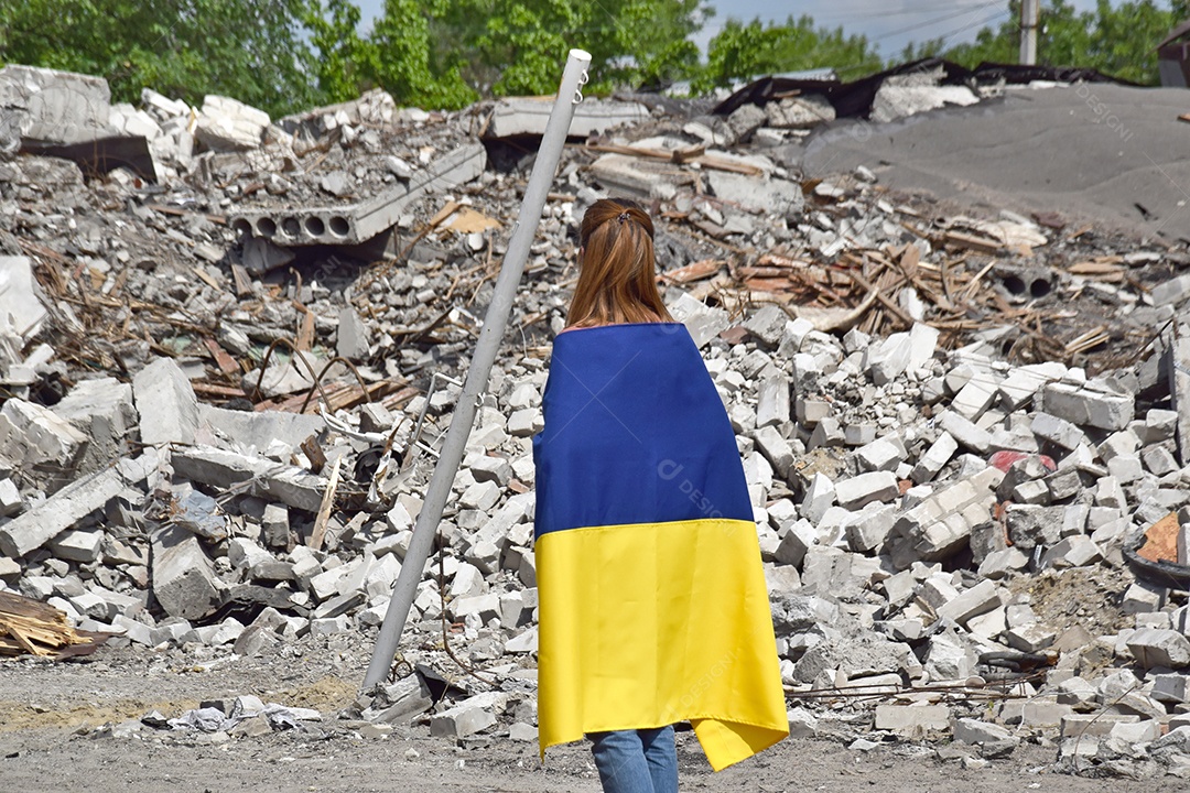 Mulher com bandeira nas costas vendo a destruição da guerra