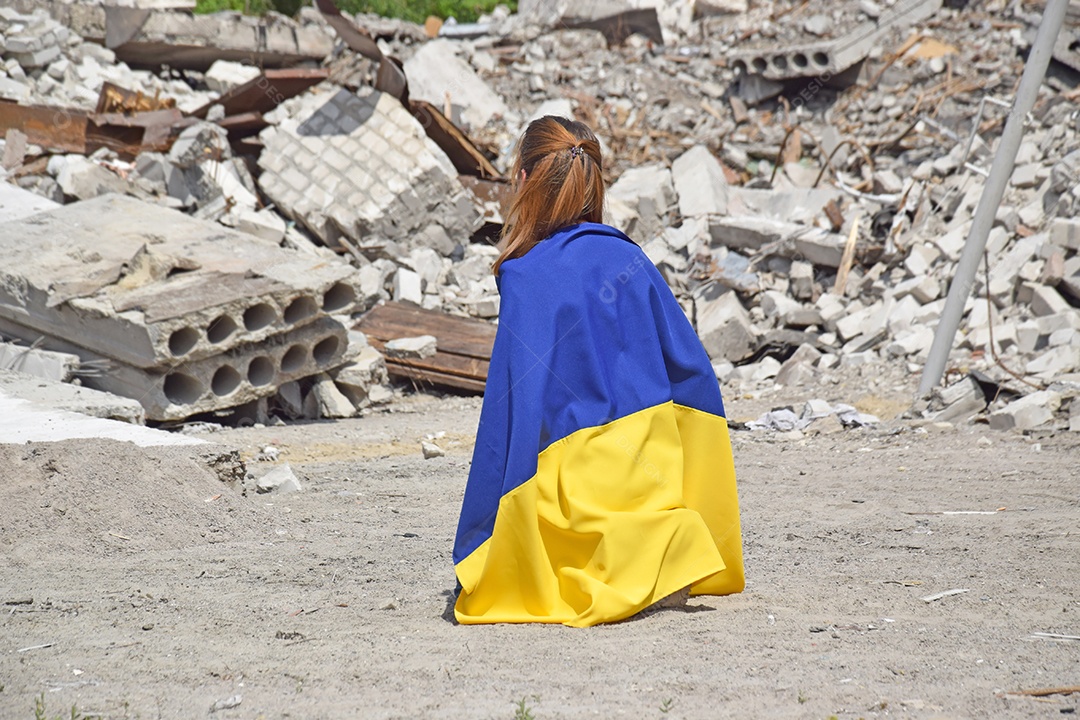 Mulher abaixada com bandeira sobre as costas na frente de destruição