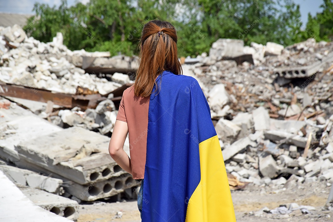 Mulher com bandeira nas costas vendo a destruição da guerra