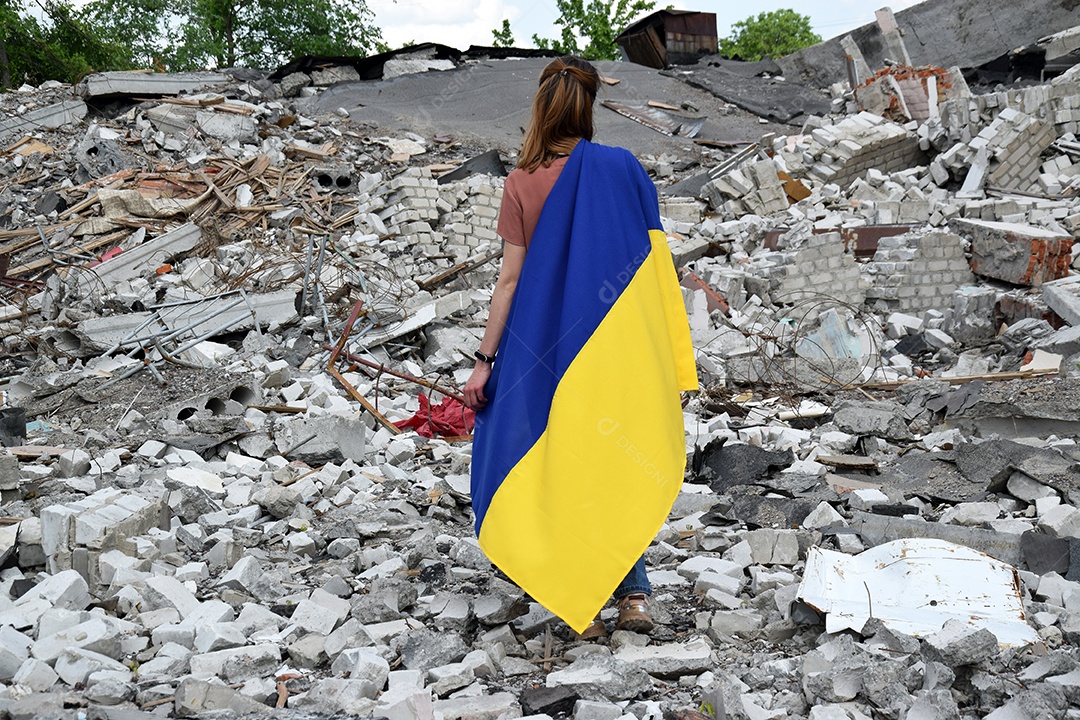 Mulher em meio a destruição causada pela guerra com bandeira da Ucrânia