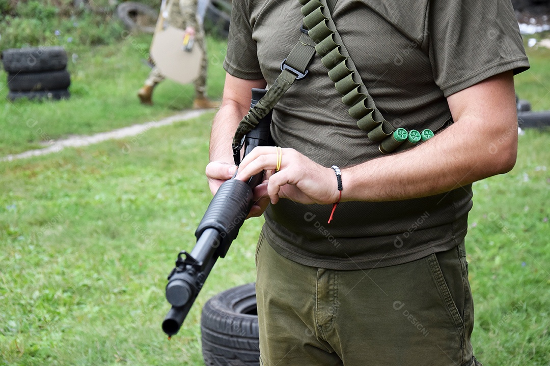 Homem segurando refle e munição cruzada em seu peito