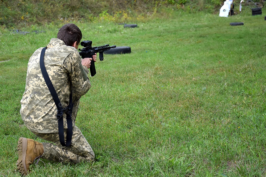 Homem de joelhos mirando em alvo