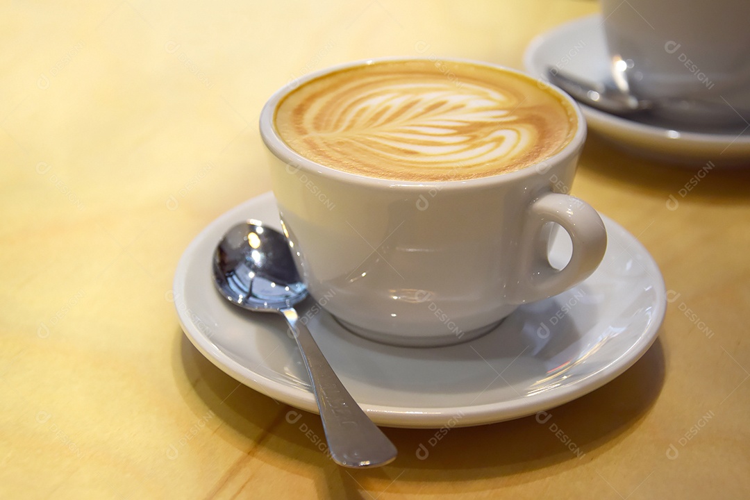 Espuma em uma xícara de cappuccino sobre uma mesa de madeira clara em um café