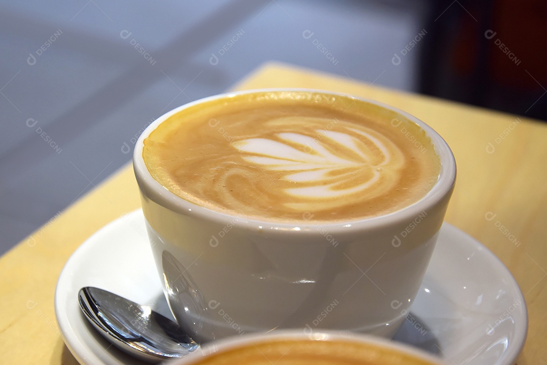 Cappuccino em xícara sobre a mesa de madeira clara