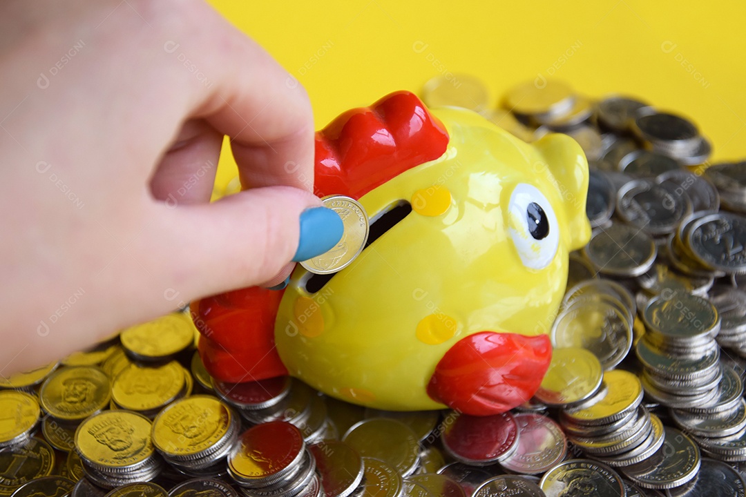 Mulher colocando moeda dentro de cofrinho amarelo