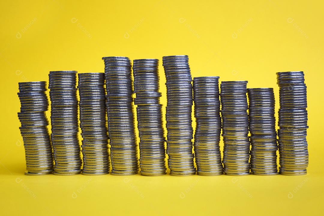Muitas moedas empilhadas sobre fundo amarelo
