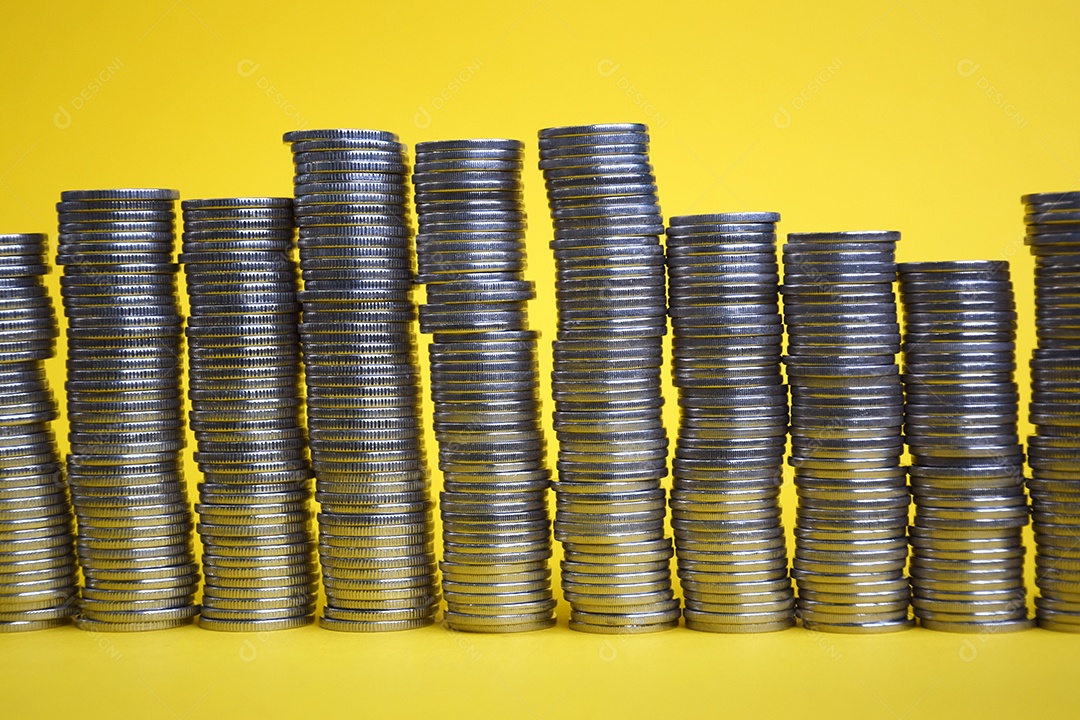 Várias pilhas de moedas sobre fundo amarelo