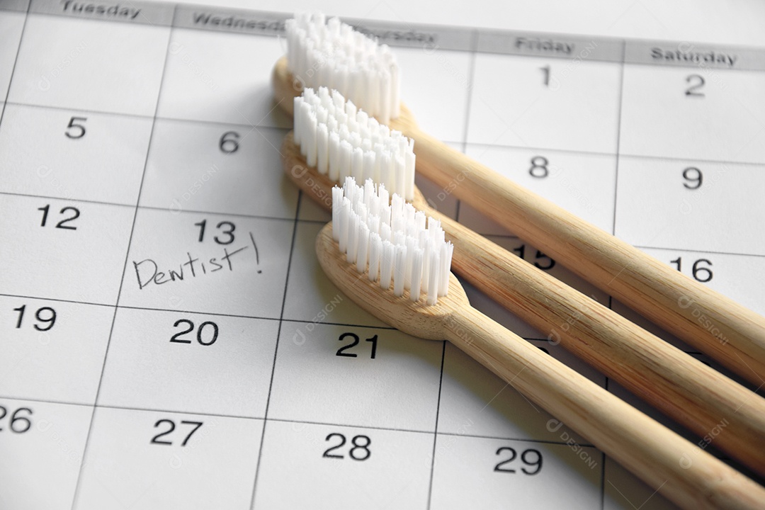 Três escovas de bambu e calendário com data marcada de dentista