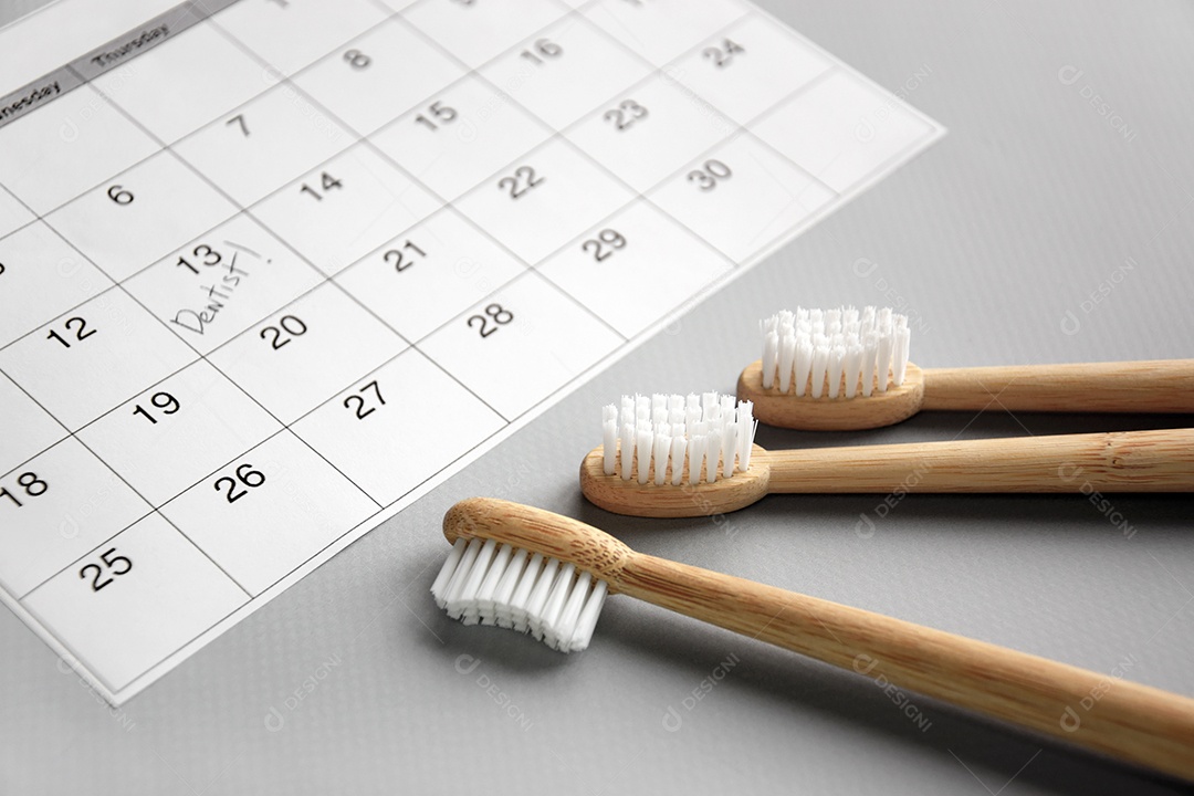 Calendário com data marcada para dentista e três escovas de bambu