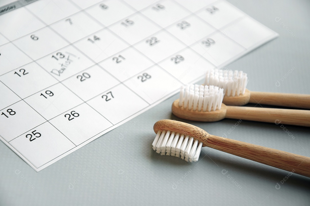 Três escovas de bambu e calendário conceito de data marcada para o dentista