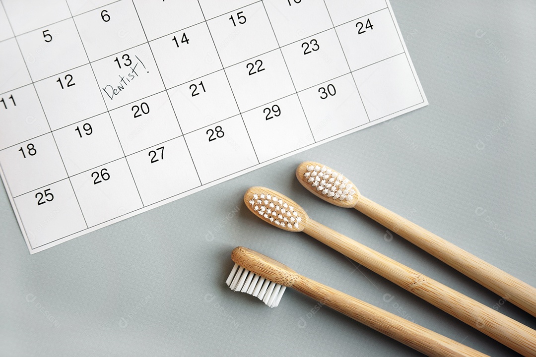 Três escovas de bambu e calendário conceito de data marcada para o dentista