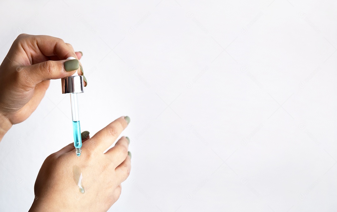 Mão segurando pipeta de vidro pingando óleo em mão