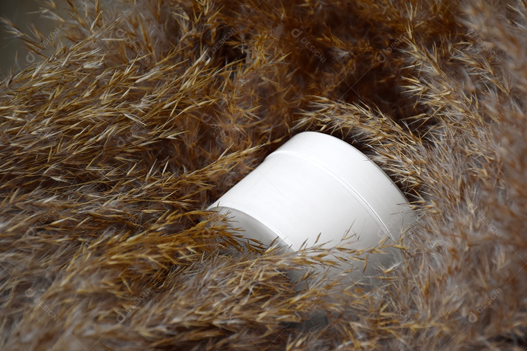 Pote de creme esfoliante para rosto e corpo sobre fundo de juncos