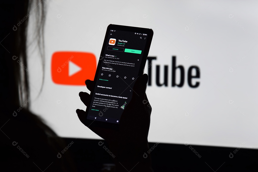Youtube em monitor e celular nas mãos de uma jovem mulher