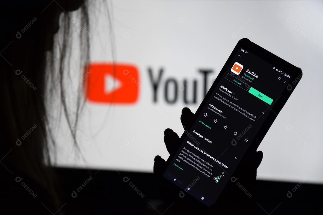 Tela Youtube em celular e monitor com mulher presente segurando celular