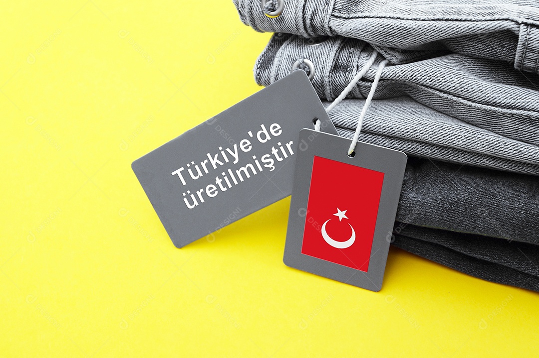 Detalhe de jeans preto etiquetas cinza e inscrição fabricado na Turquia em fundo amarelo