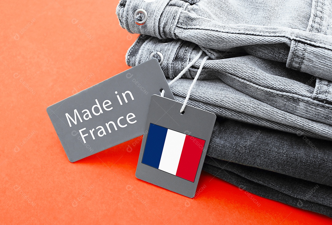 Jeans dobrados com etiquetas de feita na França sobre fundo laranjado