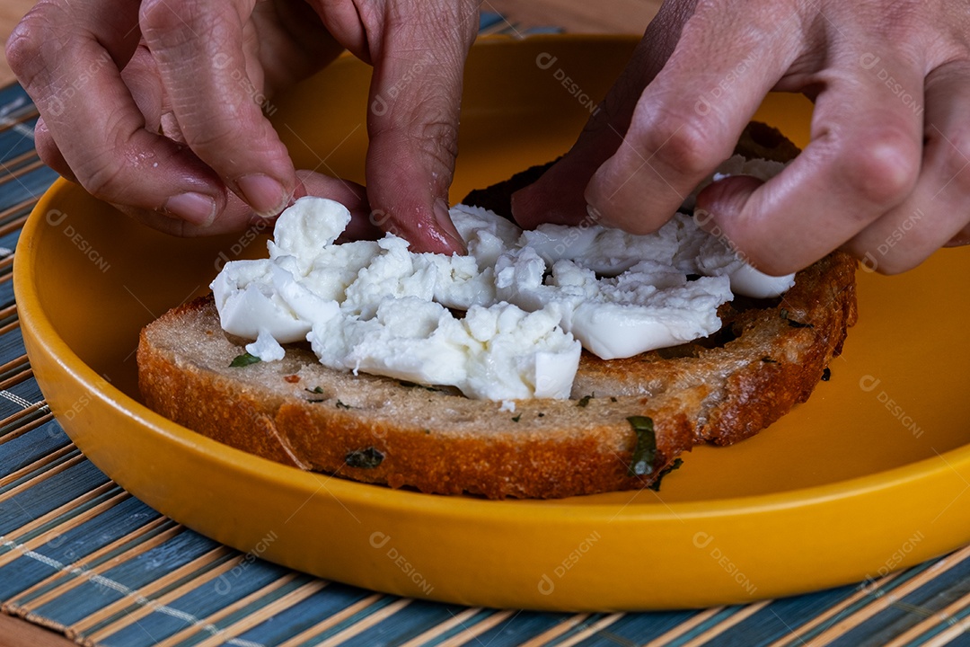 preparando um lanche com uma fatia de pão de fermentação natural, recheado com tomate
