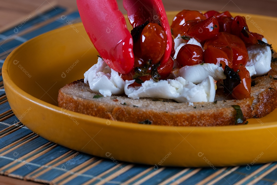 preparando um lanche com uma fatia de pão de fermentação natural, recheado com tomate
