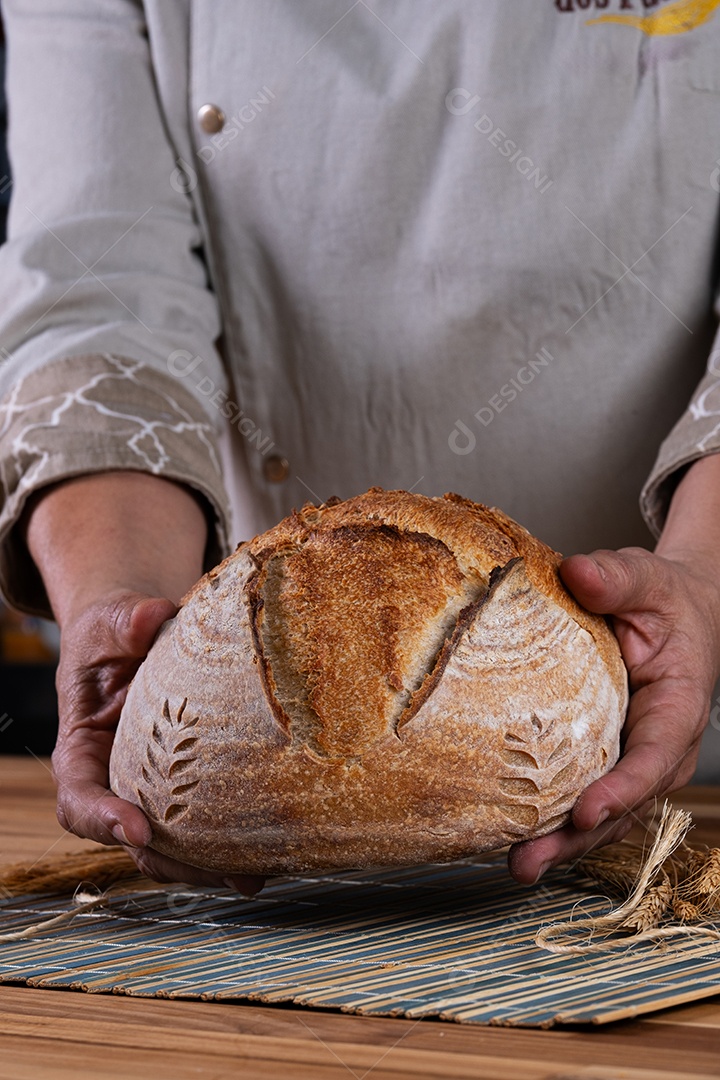 Mãos femininas segurando pão artesanal de fermentação natural.