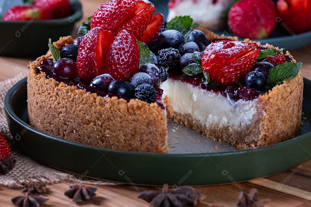 mão segurando uma fatia de torta doce com cobertura de creme e frutas.