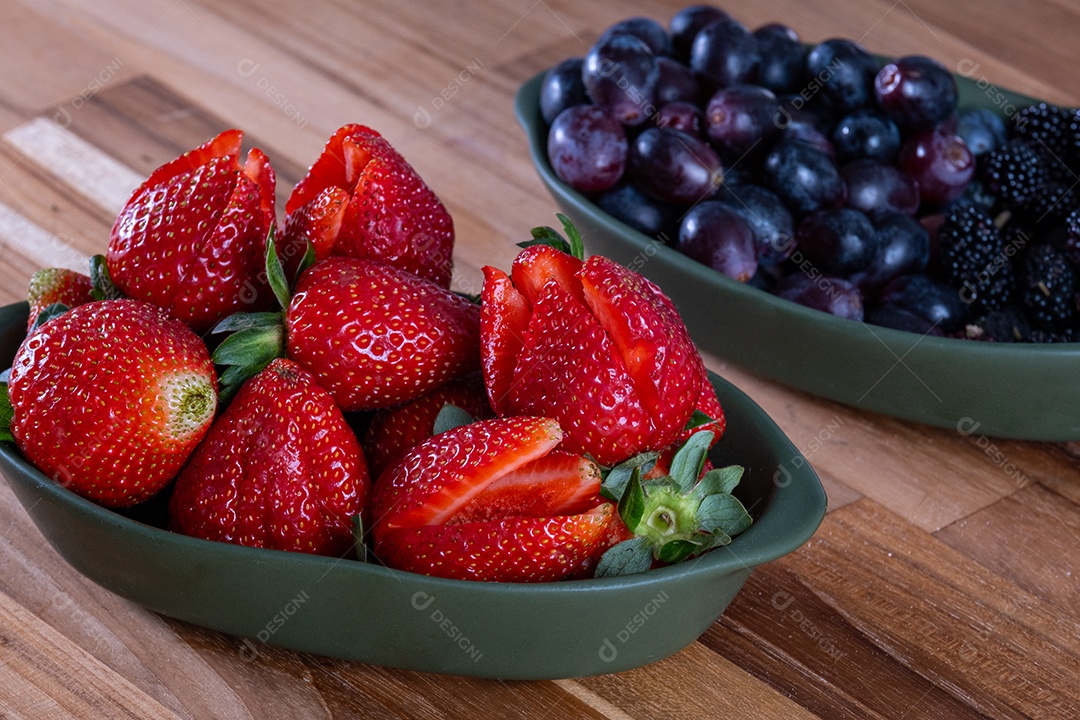 Dois recipientes ovais, um contendo morangos e outro contendo uvas e amoras.