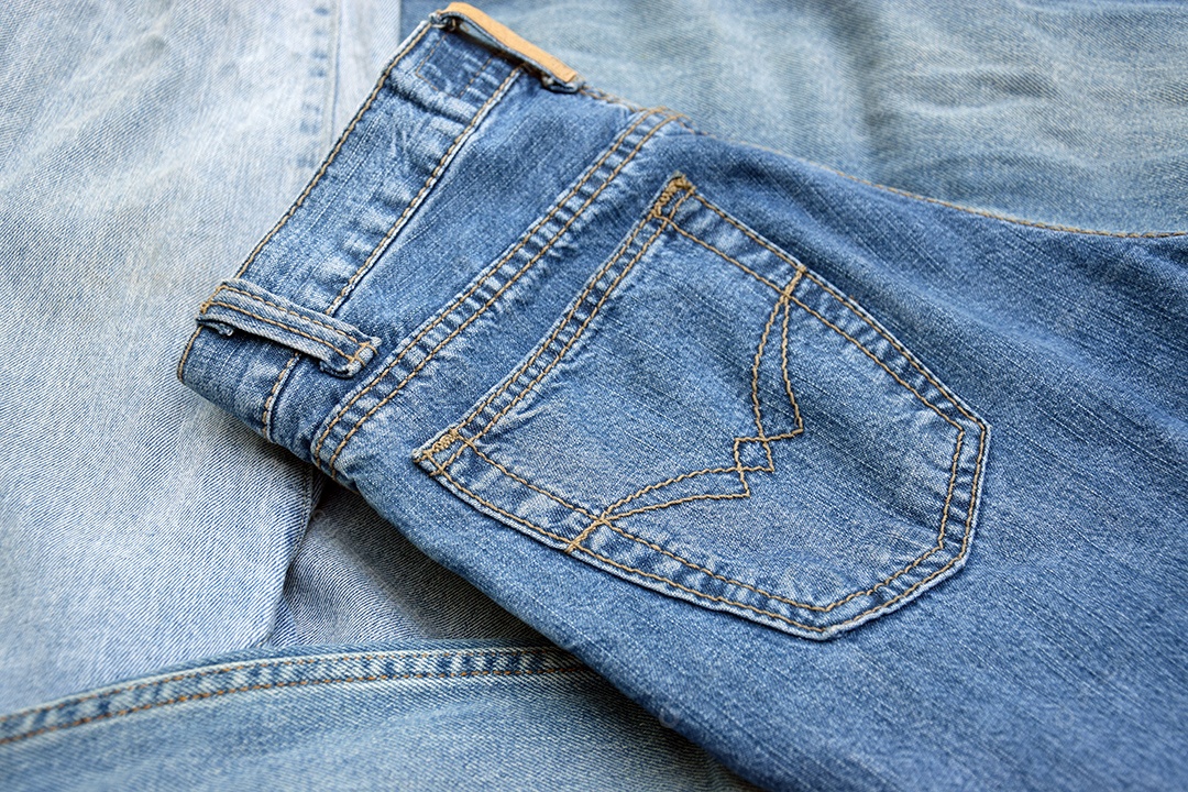 Calça dobrada com lindos detalhes de costura sobre fundo de jeans