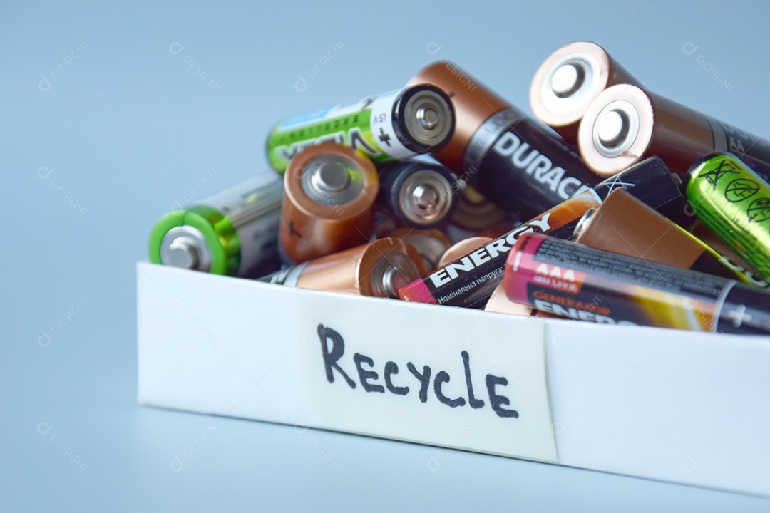 Caixa de reciclar com pilhas velhas dentro sobre fundo azul