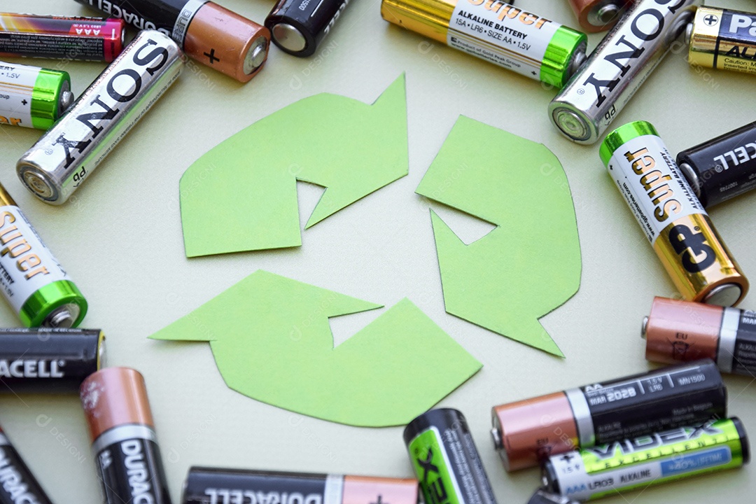 Símbolo de reciclagem ao meio rodeado de pilhas velhas