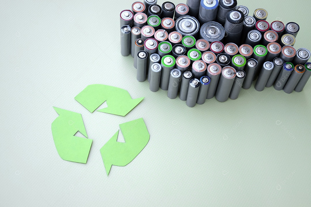 Muitas pilhas descartadas de uma lado e símbolo de reciclar ao lado