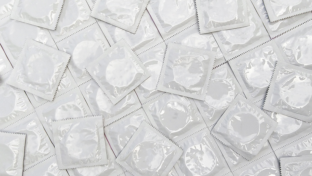 Muitos pacotes brancos de preservativos fechados