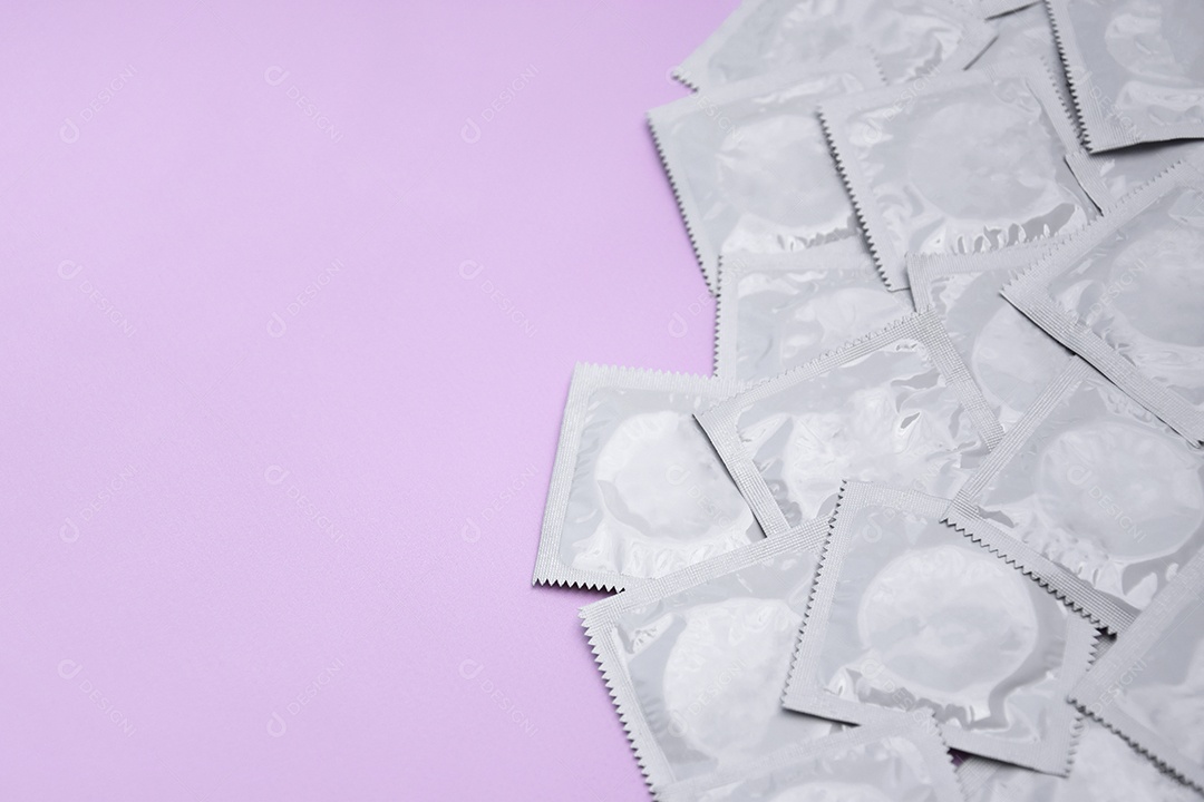 Muitas camisinhas de embalagem brancas sobre fundo rosa