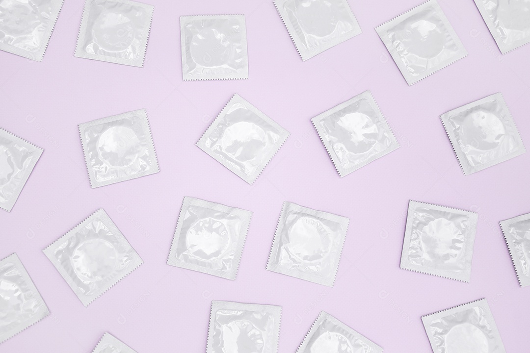 Muitas camisinhas de embalagem brancas sobre fundo rosa