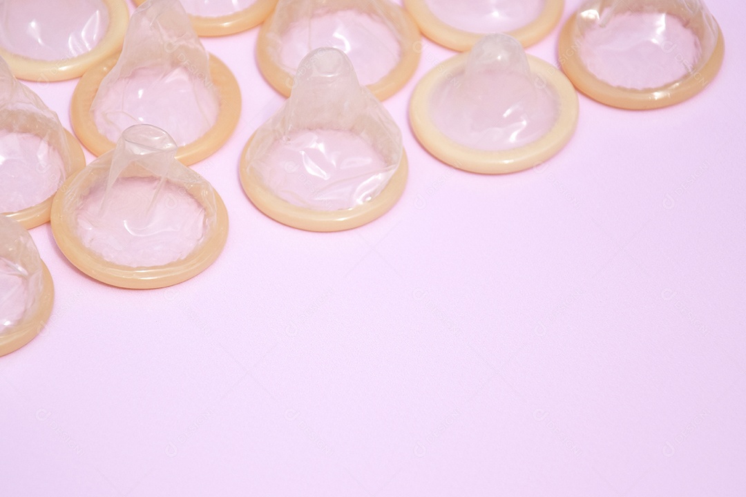 Muitos pacotes branco de preservativos fechados sobre fundo rosa