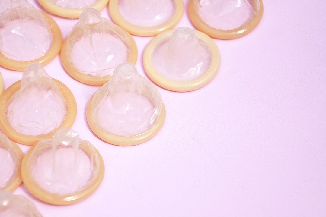Muitos pacotes brancos de preservativos fechados em um fundo rosa