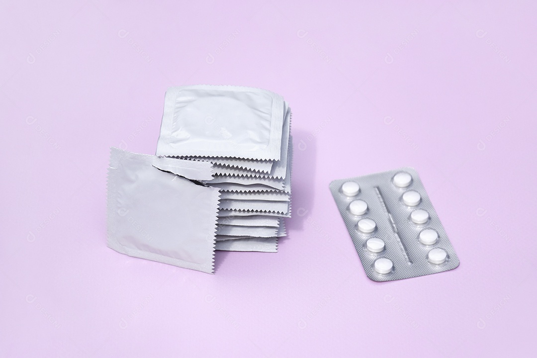 Comprimidos e preservativo sobre fundo lilás