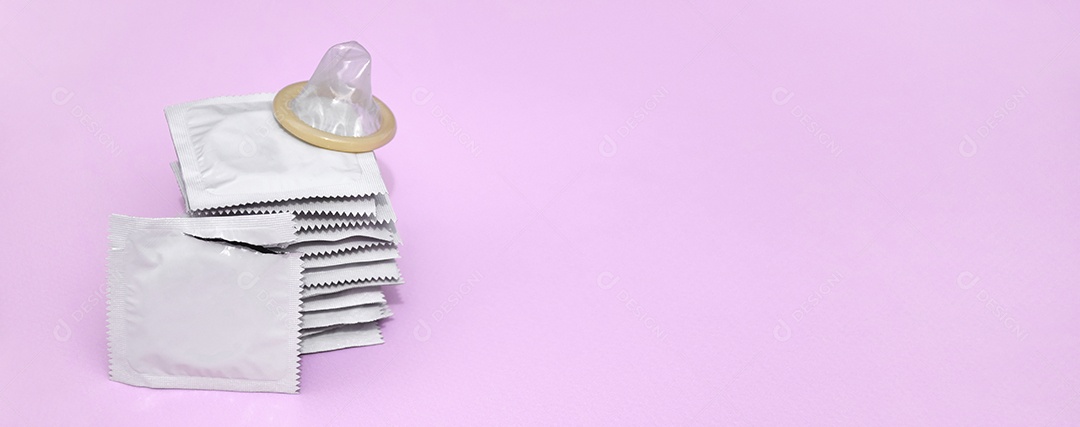 Muitas camisinhas de embalagem brancas sobre fundo rosa