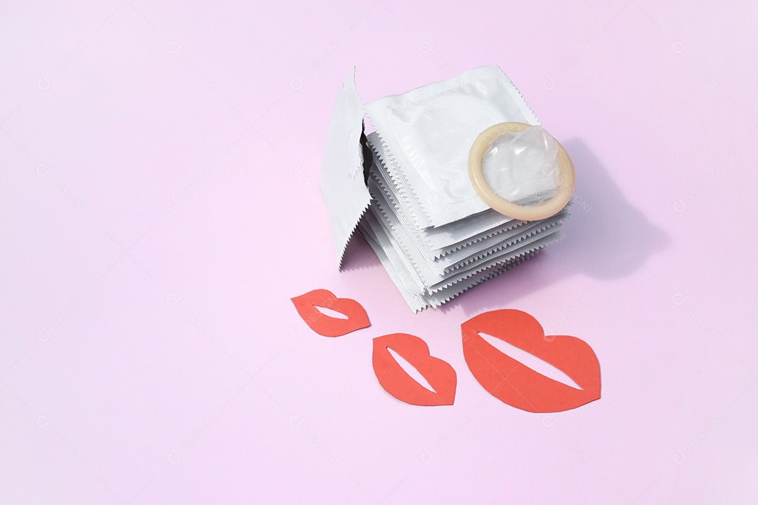 Pacote de camisinhas com uma aberta e beijos vermelhos sobre fundo rosa