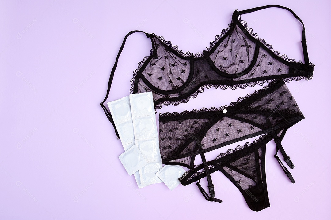 Pacotes de camisinha com lingerie de renda sobre fundo rosa