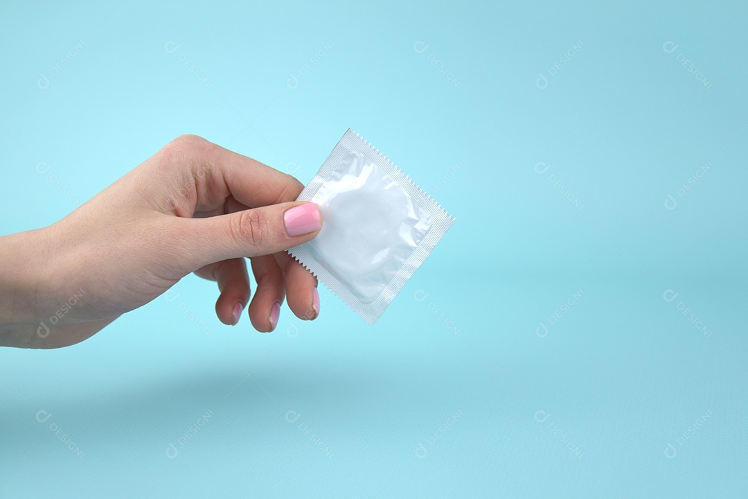 Mão segurando preservativo de embalagem branca
