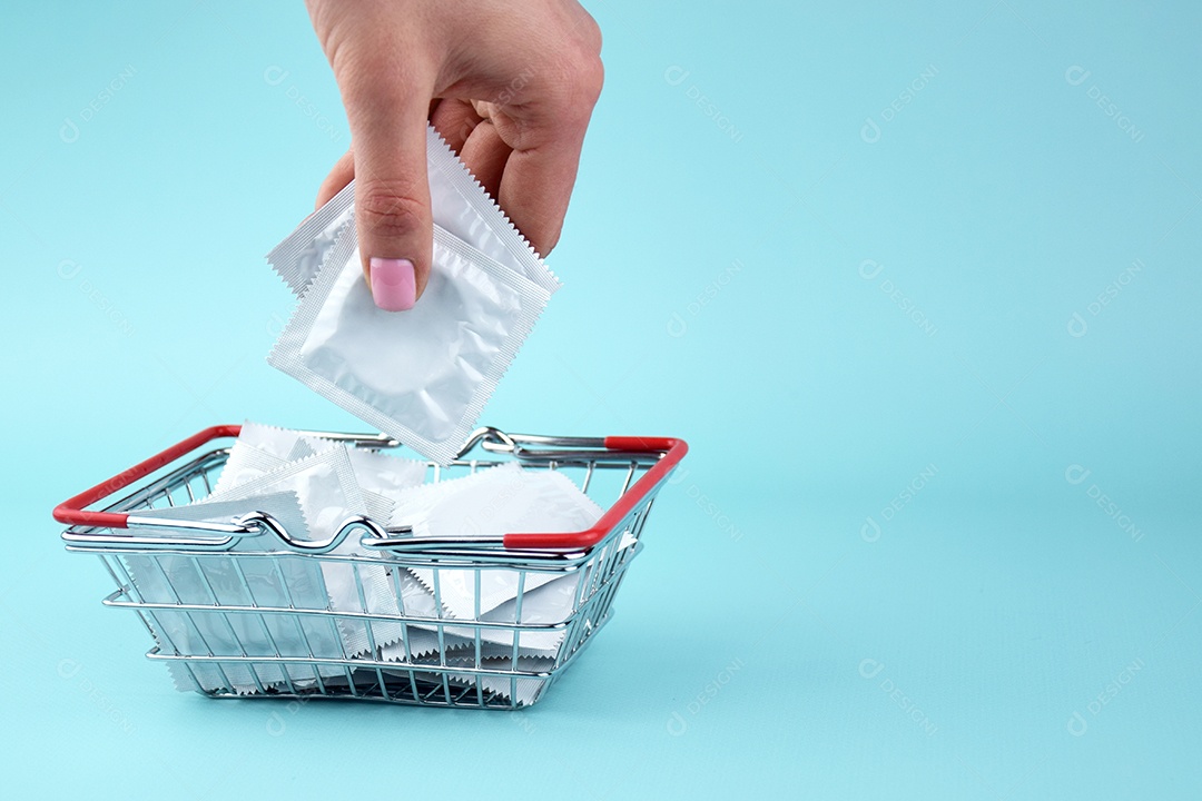 Cestinha de compra com muitos preservativos de embalagem branca dentro sobre fundo azul