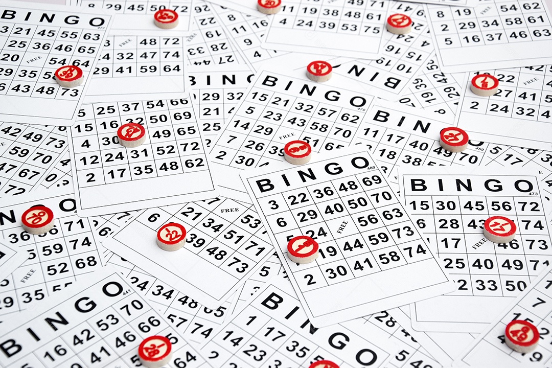 Muitas cartelas de bingo com fichas de madeira marcando