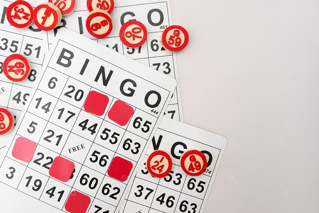 Várias cartelas de bingo e marcadores sobre fundo de marfim